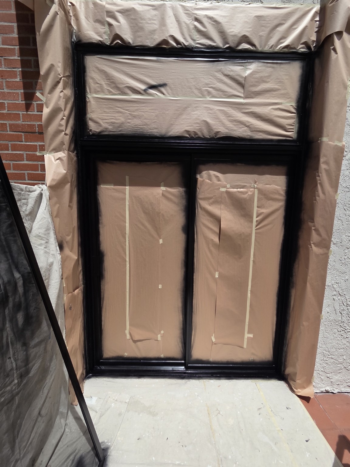 Black-framed sliding door masked and prepped for finish work